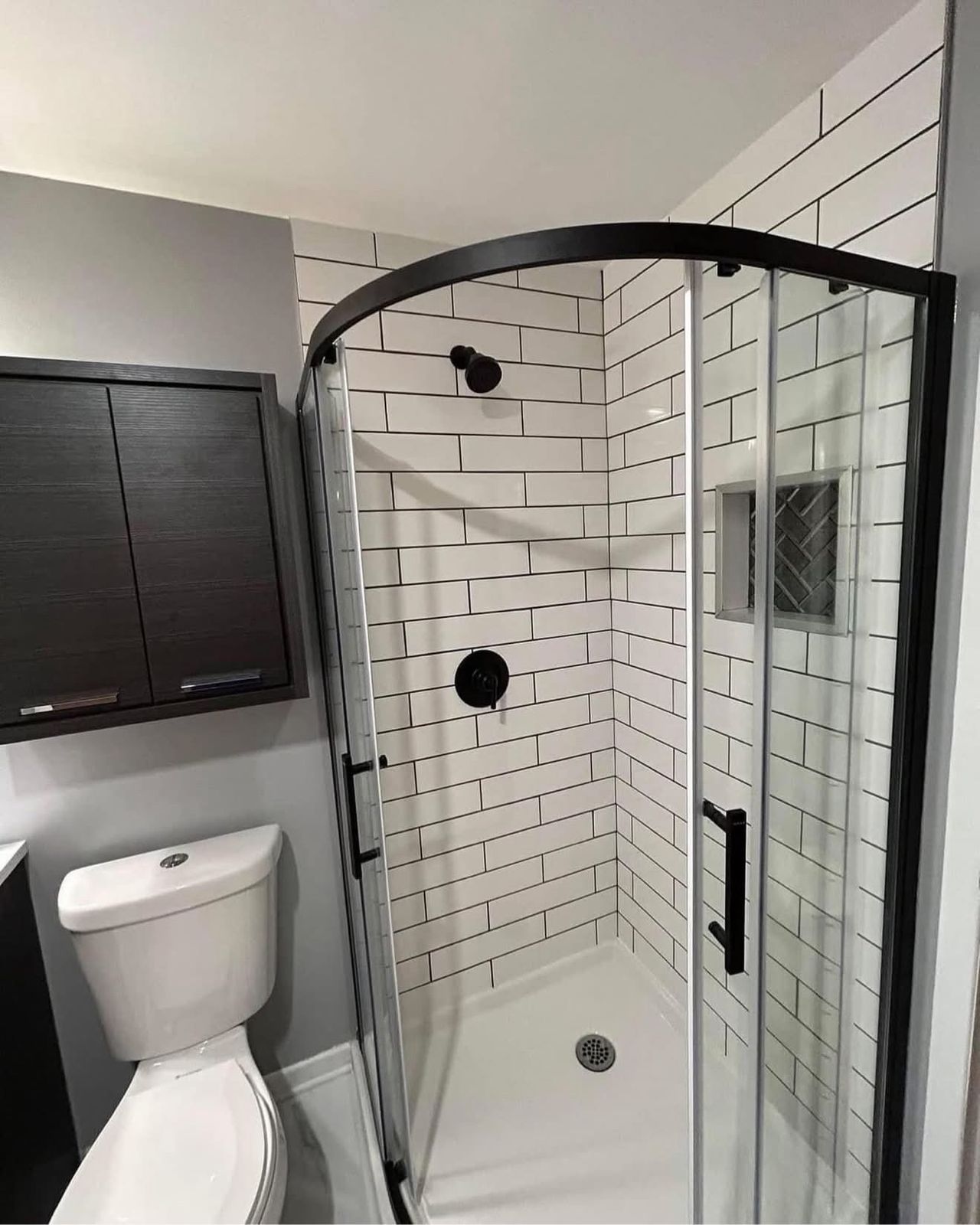 Corner shower with black fixtures and subway tile
