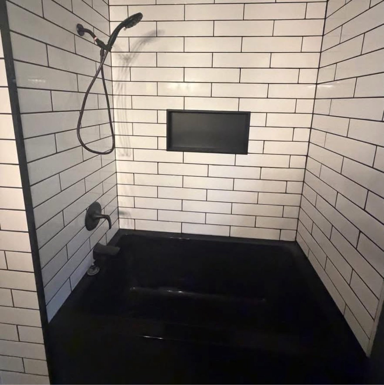 Tub and shower with black fixtures and subway tile